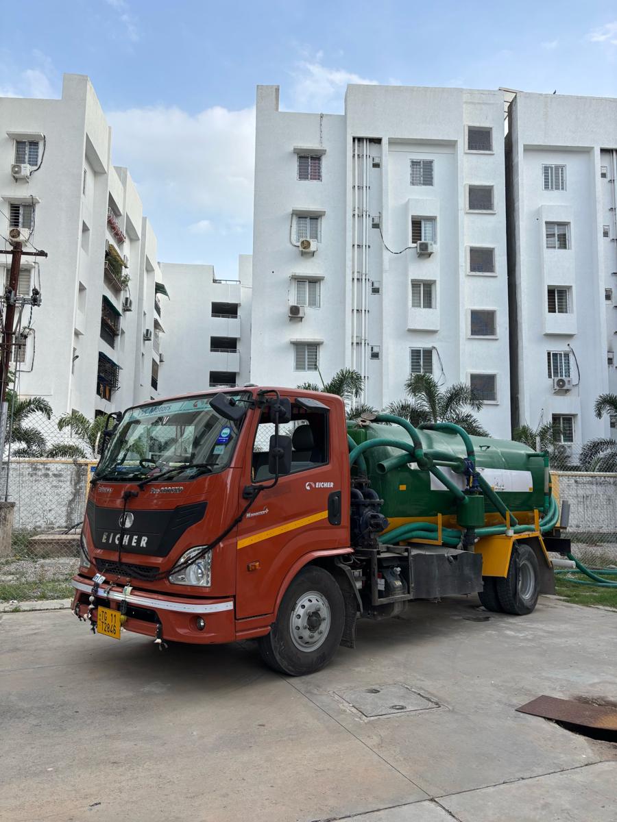 Green vacuum tanker outside an apartment complex
