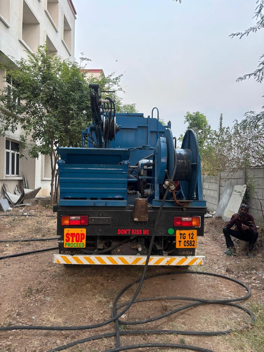Rear of grab bucket machine showing hydraulic arm and hose reel
